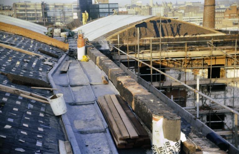 Photograph of renovation of Albert Dock, Liverpool, Block D, later Merseyside Maritime Museum, lead gutter sheeting being laid to stepped parapet gutter on north elevation of roof, looking east, with stainless steel cleats to receive cork roof insulation  card