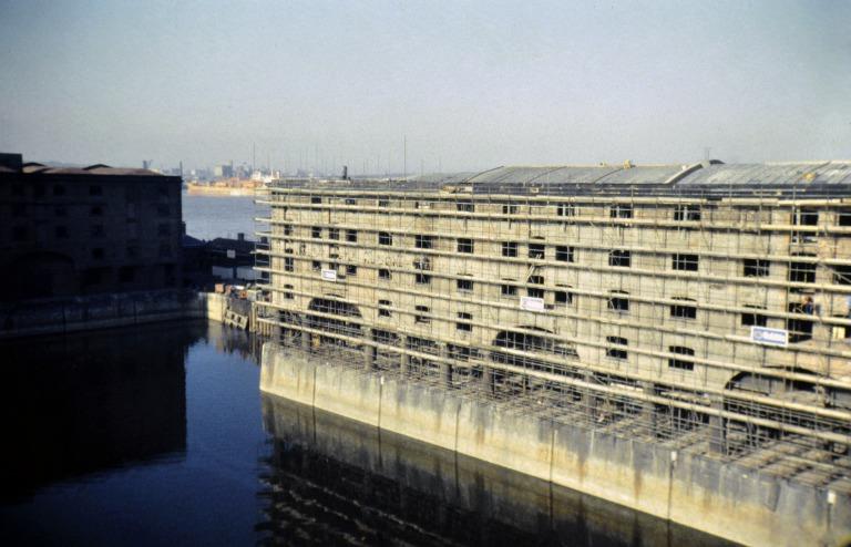 Photograph of renovation of Albert Dock, Liverpool, Block D, later Merseyside Maritime Museum, south elevation, scaffolded.  Note cold storage roof structure addiition to the west, now demolished. card