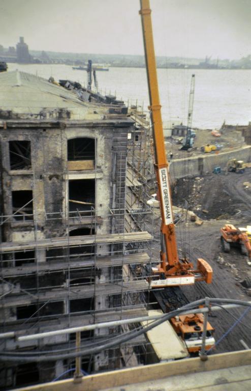 Photograph of renovation of Albert Dock, Liverpool, Block D, later Merseyside Maritime Museum, east elevation of north west corner and north courtyard looking west towards the River Mersey.  Initial clearing of infill in north courtyard, from when adapted card