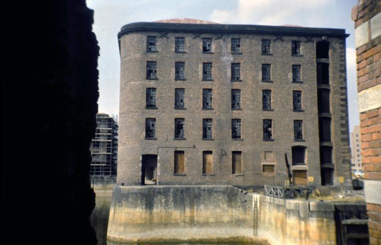 Photograph of renovation of Albert Dock, Liverpool, Block E derelict, south elevation and Block D, later Merseyside Maritime Museum, scaffolded, south east corner to centre left. card