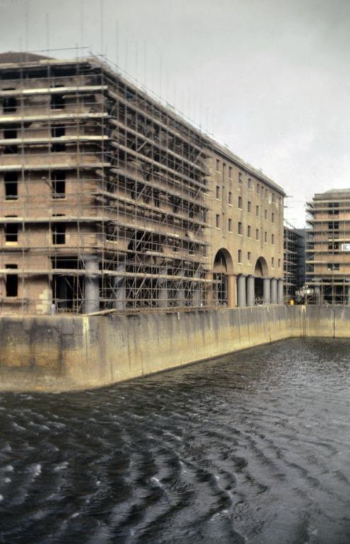 Photograph of renovation of Albert Dock, Liverpool, Block D, later Merseyside Maritime Museum, south west corner and south elevation, with west end still scaffolded and restored brickwork, viewed from Block C across Albert Dock. card